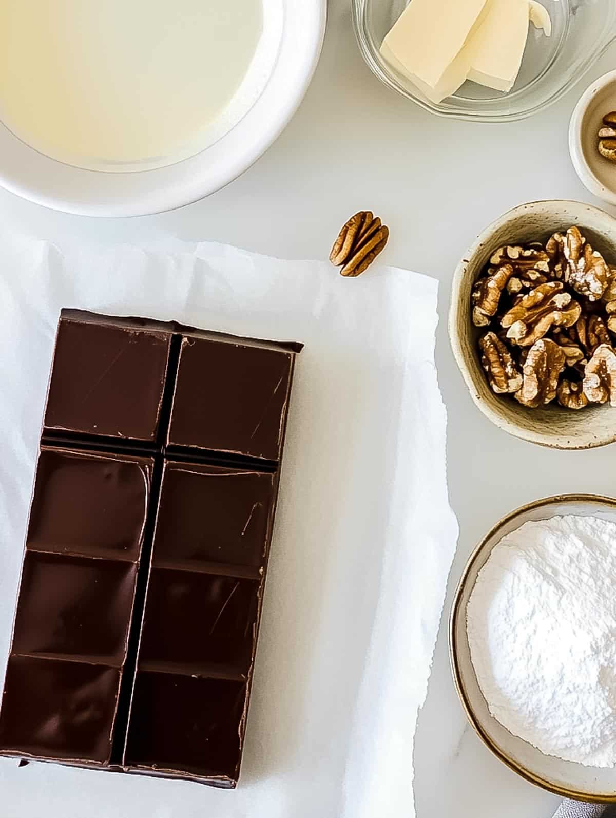 Ingredients for chocolate walnut fudge, including chocolate, walnuts, butter, and cream.