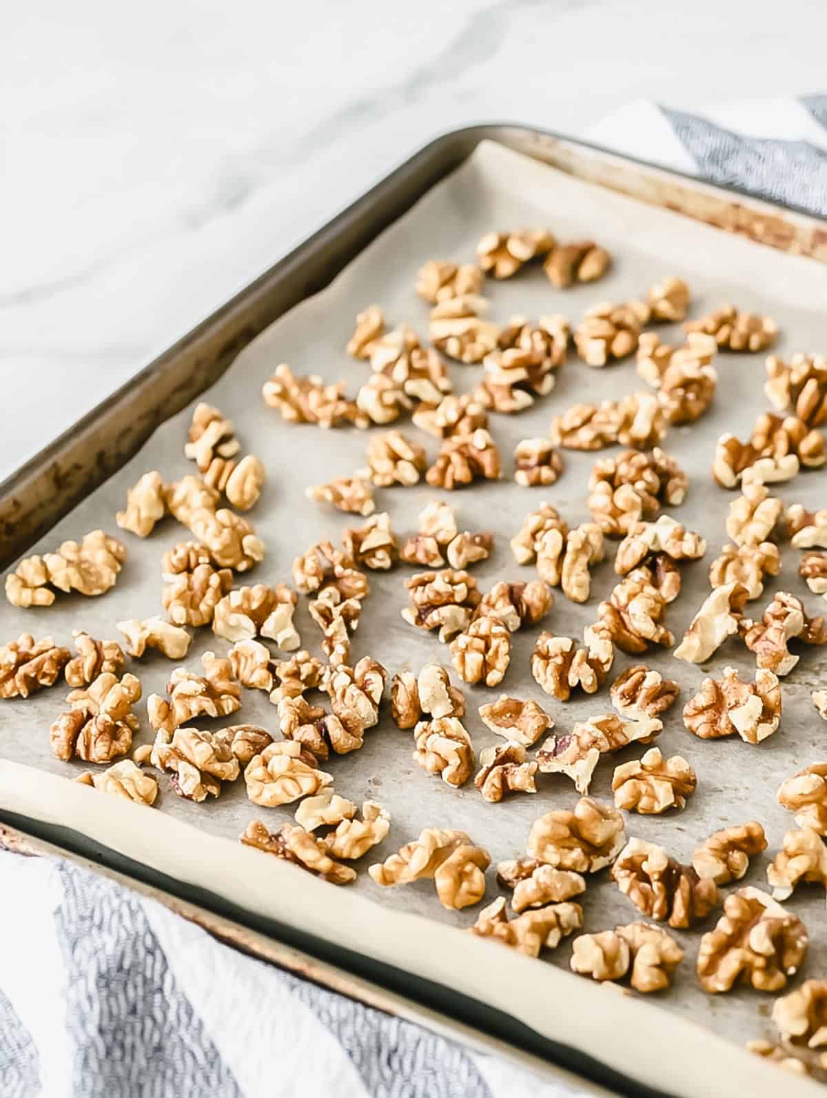 Walnuts roasting on a baking sheet lined with parchment paper.