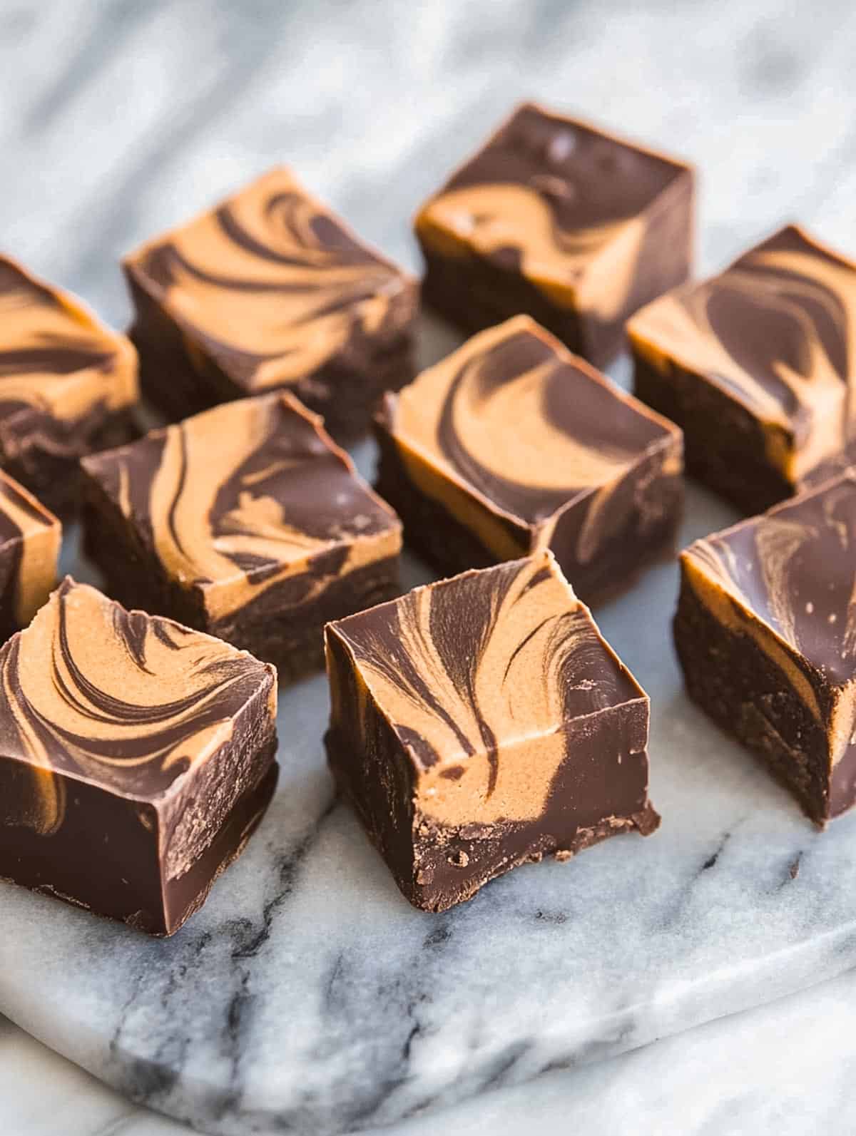 Squares of swirled chocolate and gingerbread fudge on a marble slab.