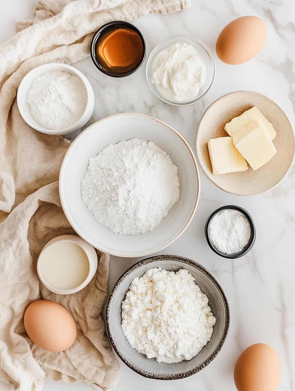 Flat lay of ingredients for protein pancakes, including flour, sugar, Greek yogurt, butter, and eggs.