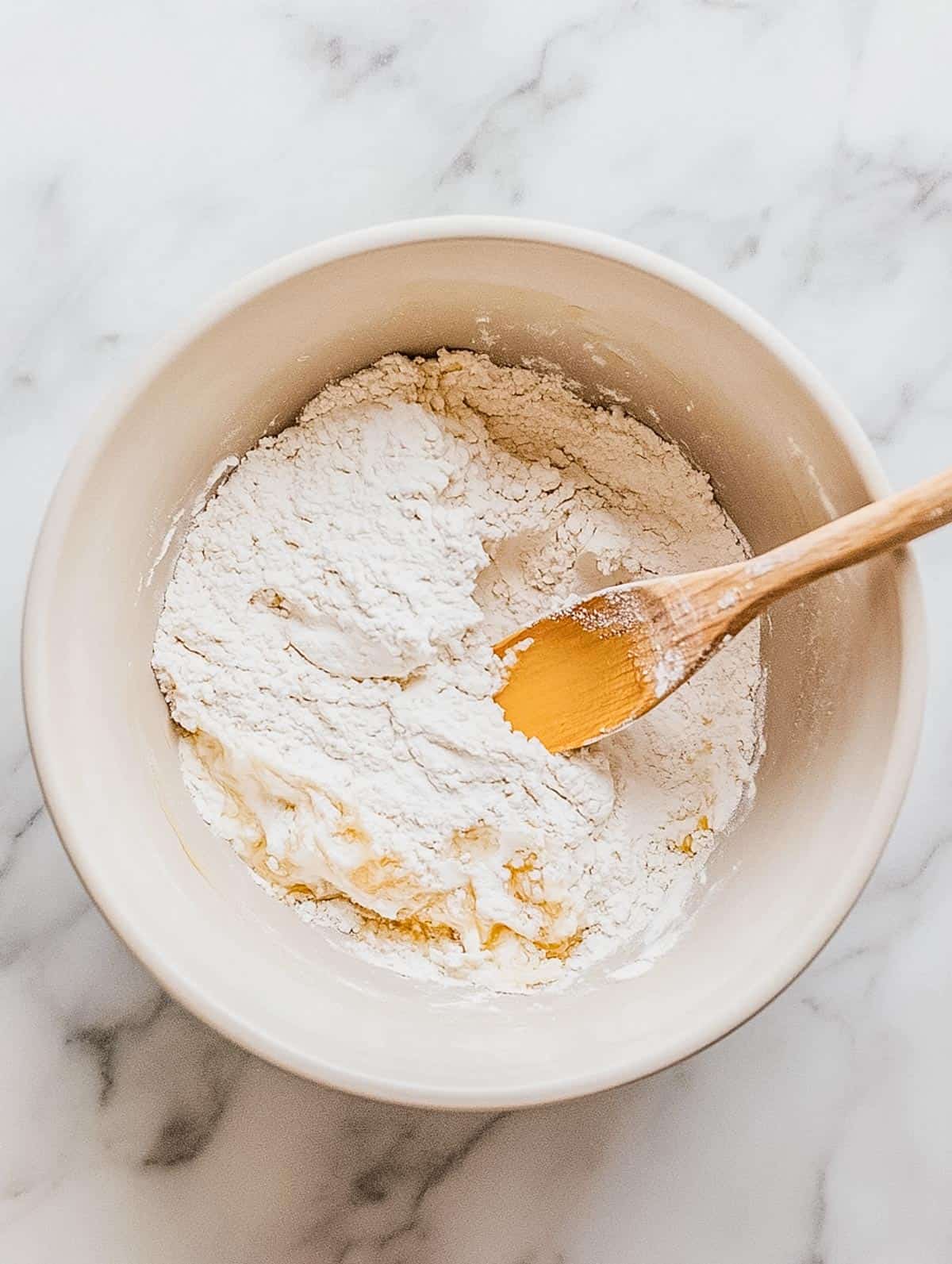 Bowl of pancake batter being mixed with a wooden spoon.