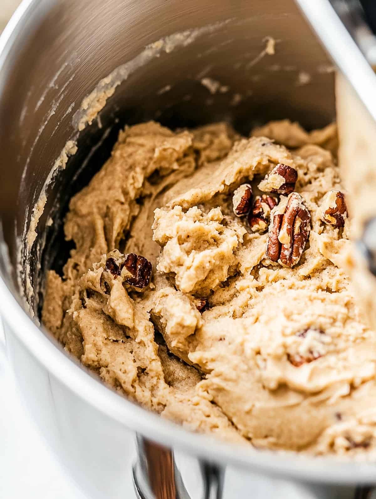 A stainless steel bowl filled with maple pecan cookie dough, ready for shaping.